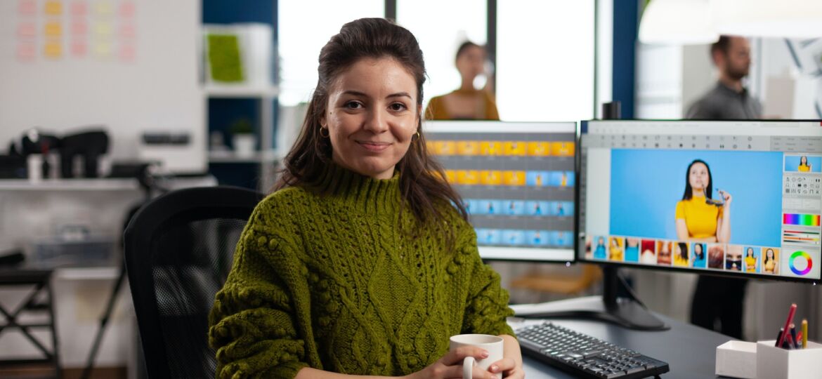 Woman retoucher looking at camera smiling sitting in creative design media agency